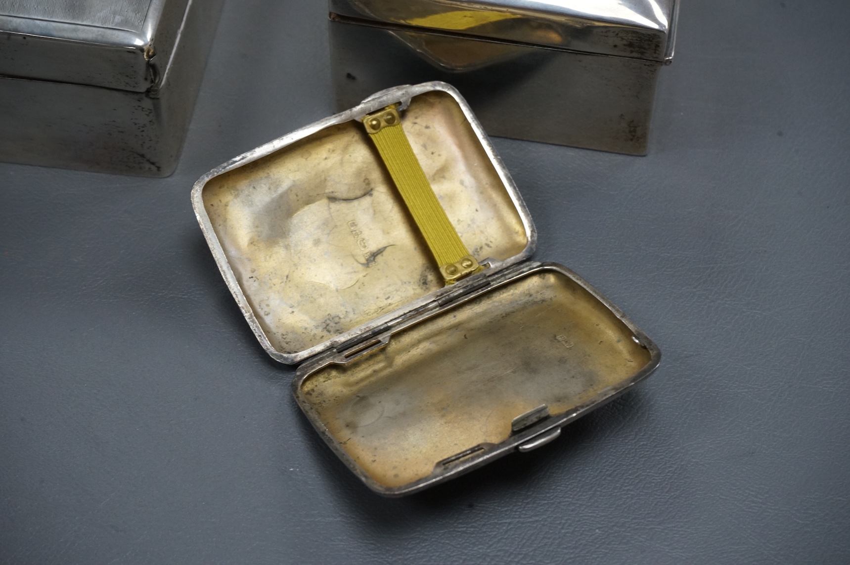 A George V silver mounted rectangular cigarette box, London, 1924, width 16cm, together with a smaller silver mounted cigarette box and a silver cigarette case.